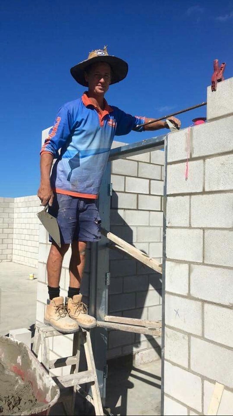 Australian bricklayer rendering a besser-block wall on site