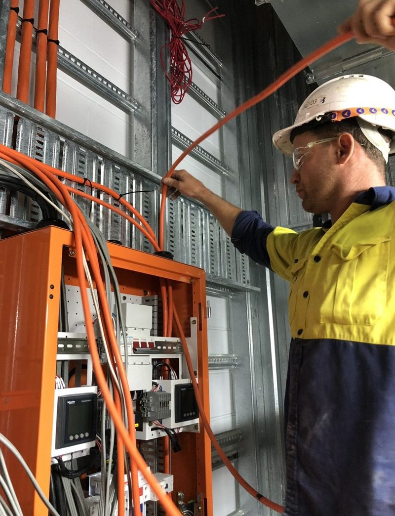Australian electrician wiring an orange switchboard