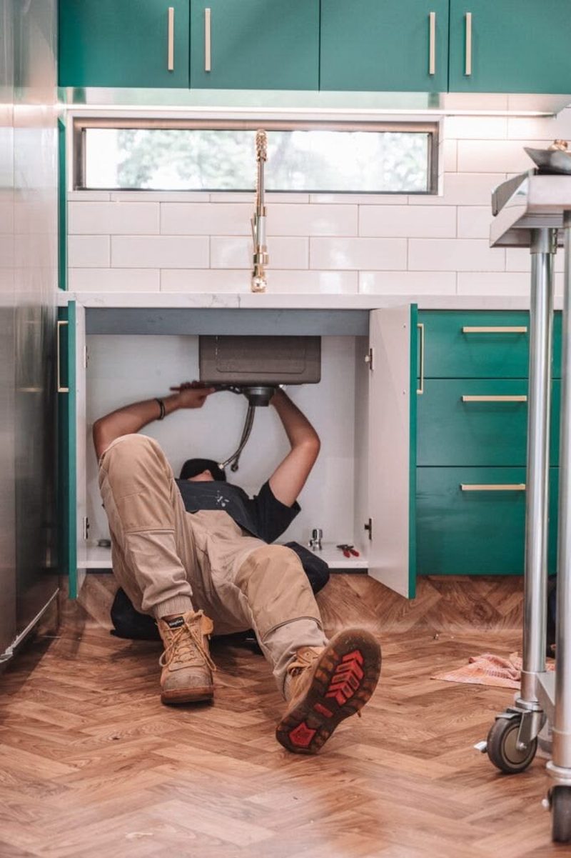Australian plumber working under a kitchen sink